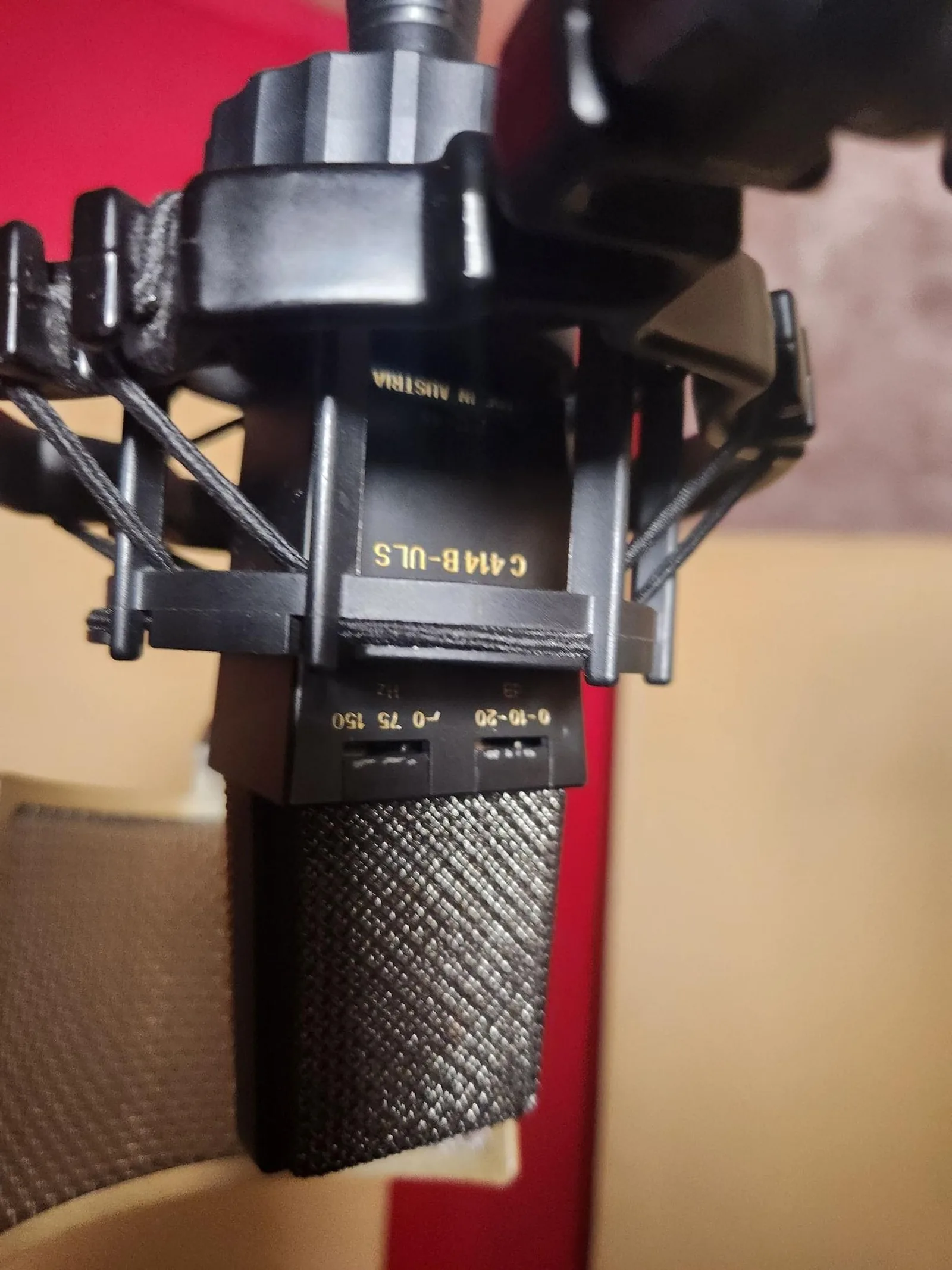 Photo of an AKG C414 B-ULS large-diaphragm condenser microphone showing the body with polar-pattern selector switch, pad switch, and high-pass filter switch.