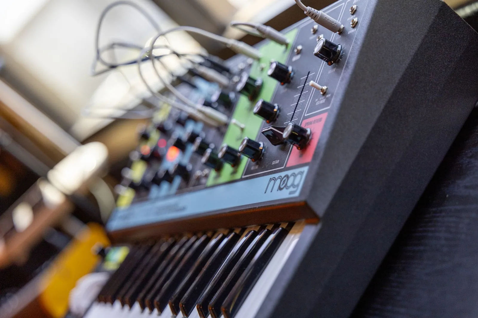 Photo of a Moog Grandmother semi-modular analog synthesizer, showing the keyboard, panel knobs, patch bay with cables, and ladder filter controls.