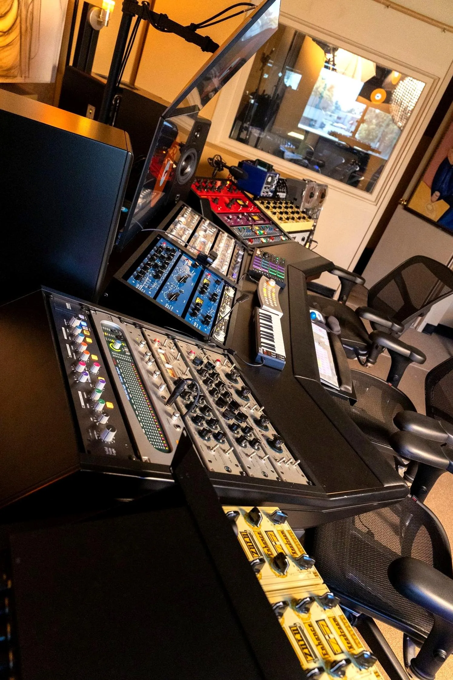 Photo of a studio mix position showing the engineer's desk, a mixing console, studio monitors, and outboard gear in a professional control room.
